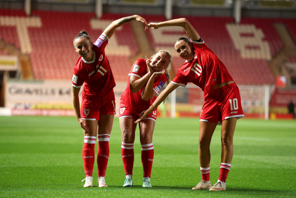 Mayzee Davies (centre) celebrates scoring her sides first goal with Hannah Cain and Mared Griffiths (Credit: FAW)